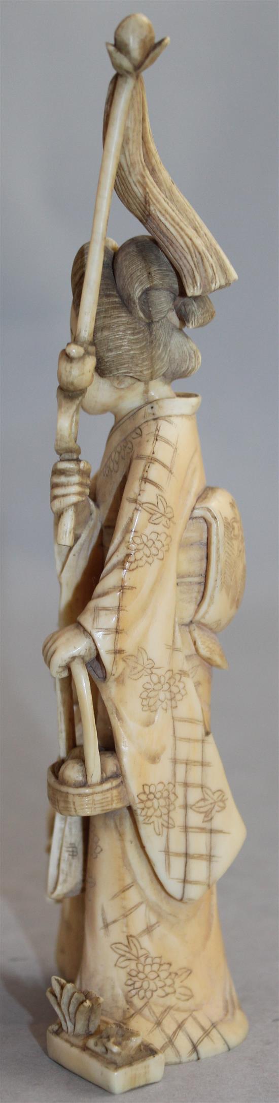 A Japanese ivory group of a woman carrying a basket of pomegranates, Meiji period, 16.8cm